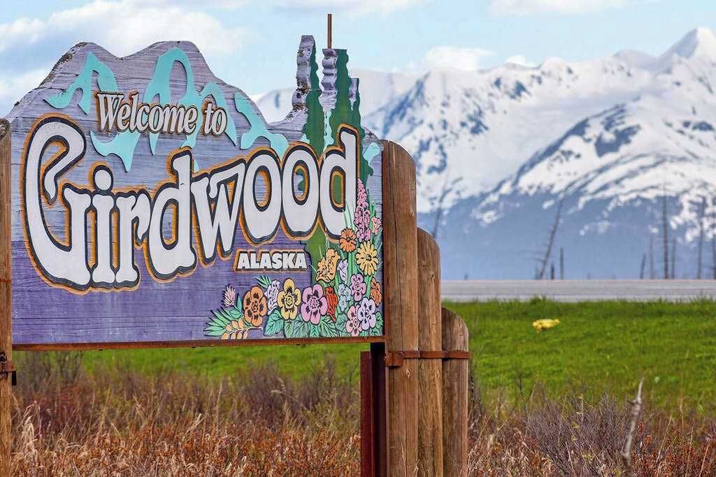 A wooden sign with 'Welcome to Chindwood Alaska' and floral decorations.