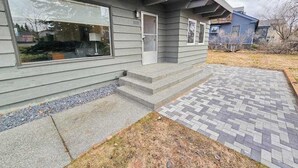 Een modern herenhuis met een veranda, een kleine voortuin en een geplaveid pad.
