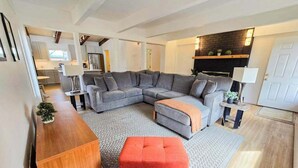 Een moderne woonkamer met een modulaire bank, een poef en een houten salontafel.
