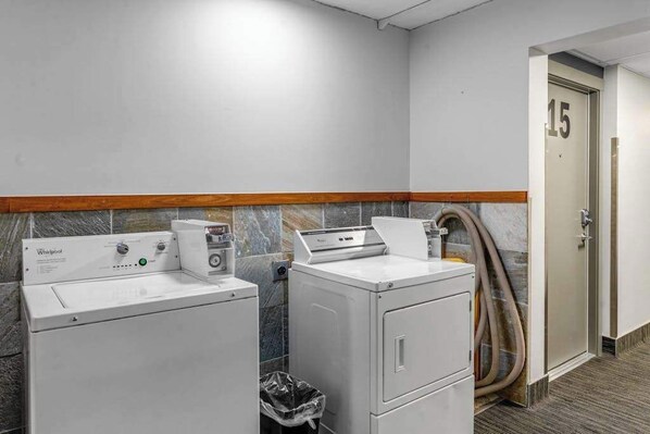 A laundry area with two Whirlpool washers, a trash bin, and a door marked with the number 15. - Olympic Loop 405S | Ski-In/Ski-Out Condo | Fireplace & Balcony (Girdwood)