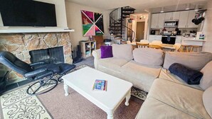 Una sala de estar con chimenea, un sofá, una mesa de centro y un televisor.