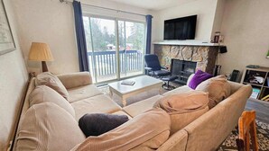 Una sala de estar con un sofá, una mesa de centro, un televisor y una chimenea.