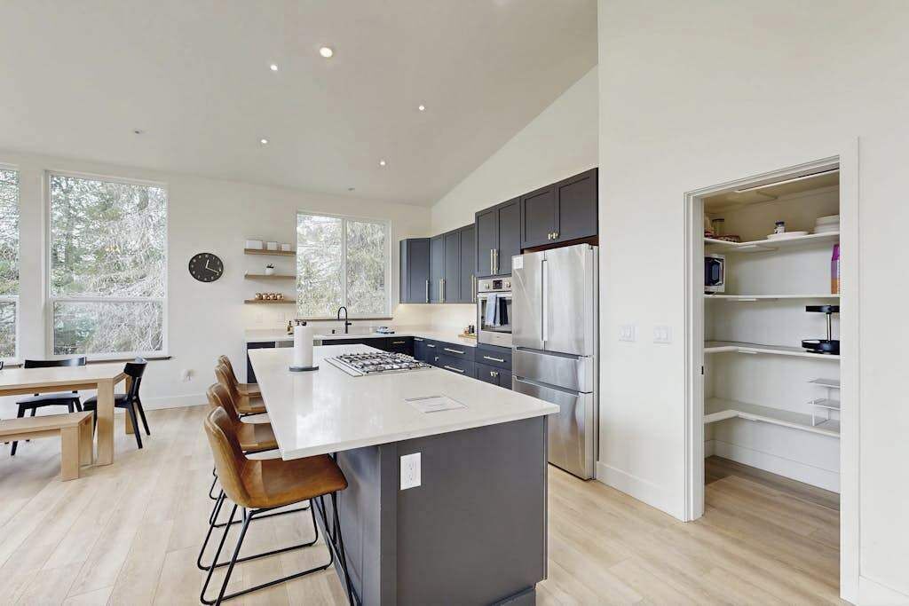 A modern kitchen with a central island, dark cabinets, and a stainless steel refrigerator.