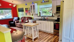 Une cuisine dotée d’un plan de travail en bois, de meubles blancs, d’une cuisinière et d’un coin repas avec un canapé en cuir marron.