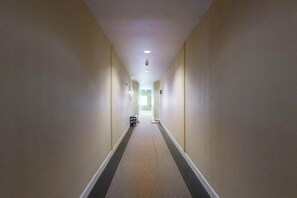 Un long couloir étroit, doté d’un sol recouvert de moquette et de murs blancs.