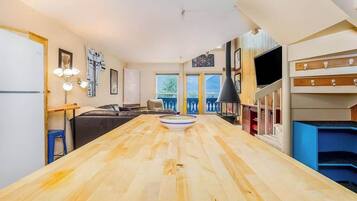 A modern kitchen with a wooden countertop, a dining area with a sofa, and a balcony with a view.