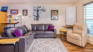 Una sala de estar moderna con un sofá modular, una mesita, una silla y una alfombra estampada.