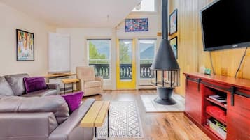 Una sala de estar con sofá, televisor, chimenea y balcón con vistas.