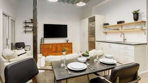 Una cucina moderna con mobili bianchi, forno integrato e zona pranzo con tavolo apparecchiato per due.