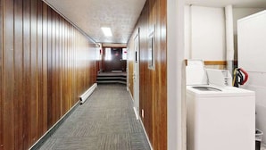 Ein Hotelkorridor mit Holzvertäfelung, Teppichboden und einer weißen Waschmaschine.
