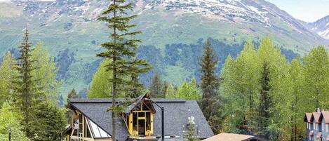 A lodge with a mountain backdrop, featuring a prominent building with a sloped roof and a smaller structure with a gabled roof.