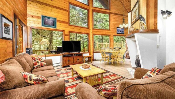 Een gezellig interieur van een chalet met een grote televisie, houten meubels en een eethoek.