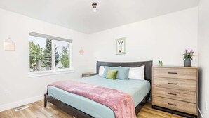 Ein Schlafzimmer mit einem Bett, einem Schminktisch, einem Fenster und einer wandmontierten Leuchte.