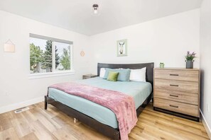 Ein Schlafzimmer mit einem Bett, einem Schminktisch, einem Fenster und einer wandmontierten Leuchte.