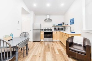 Eine kleine Küche mit Esstisch, Stühlen, einem Kühlschrank, einem Backofen, einer Mikrowelle und einem Spülbecken.