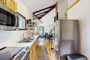 A modern kitchen with stainless steel appliances, wooden cabinets, and a built-in oven. - Girdwood Mountain House | Privacy | Tall Ceilings (Girdwood)