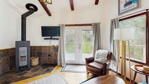 A cozy room with a fireplace, a leather sofa, a television, and a large window.