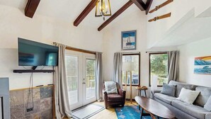 A living room with a TV, sofa, armchair, and a fireplace.