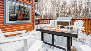 Eine Holzhütte mit Terrasse, Sitzgelegenheiten im Freien und einem Feuerkorb.