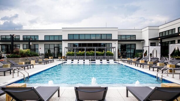Et moderne hotel med swimmingpool, liggestole og et overdækket opholdsområde.