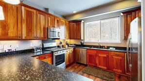 Una cucina moderna con mobili in legno, elettrodomestici in acciaio inossidabile e un'ampia finestra che garantisce luce naturale.