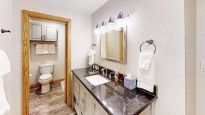 A bathroom with a sink, mirror, towel rack, and toilet. - North 409 | Ski-In/Out | Vintage Ski Decor (Anchorage)