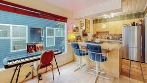A modern kitchen with a large island, bar stools, and a piano. - Bootlegger's Bohemian | Art-Curated Loft (Anchorage)