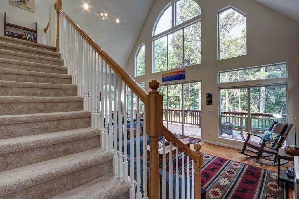 Un escalier avec une rampe en bois menant à un balcon d’où l’on peut admirer la vue sur les arbres.