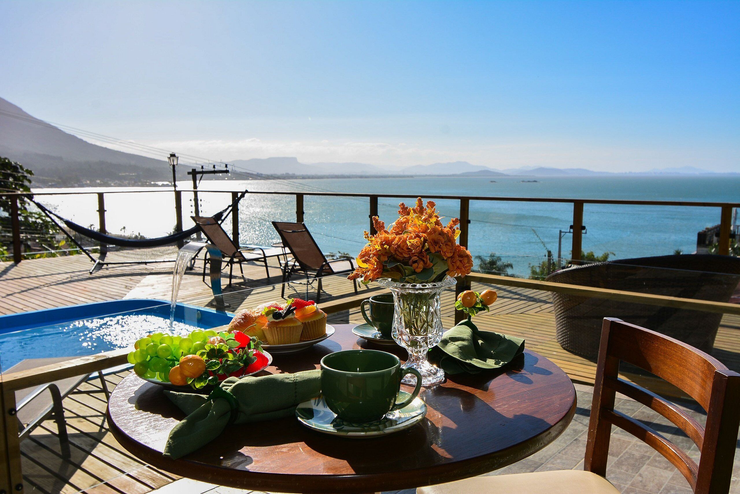 Uma mesa de jantar com vista para o oceano, uma rede e uma piscina.