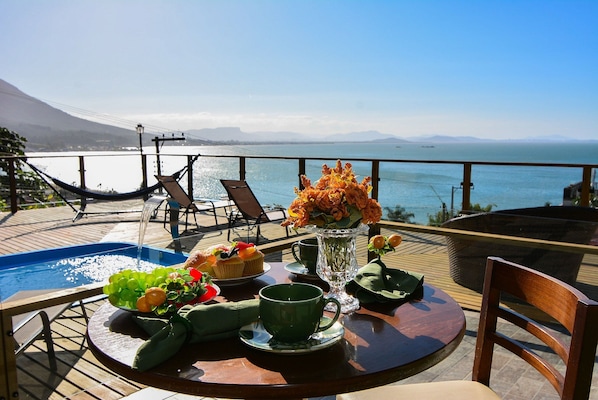 A dining table with a view of the ocean, a hammock, and a pool.