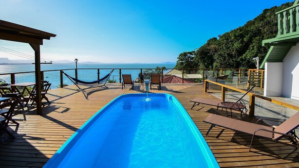 Zona de piscina con sillones de descanso y vista al mar.