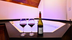 Una habitación con techo de madera, pared blanca y encimera negra con dos copas de vino y una botella.