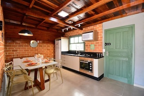 A kitchen with a dining table, chairs, a refrigerator, oven, and a green door.