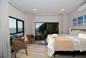 Ein Schlafzimmer mit Bett, Stuhl, Nachttisch und Meerblick.