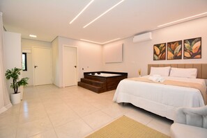 Een moderne slaapkamer met een groot bed, een inbouwhaardbad en een kamerplant.