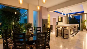 A modern dining area with a long table, chairs, and pendant lighting. - Luxury 7BR Estate w/Private Pool in Puerto Plata (Star Hill)