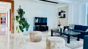 A modern living room with a flat-screen TV, a black sofa, a coffee table, and a potted plant. - Luxury 7BR Estate w/Private Pool in Puerto Plata (Star Hill)