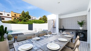 An outdoor dining area with a table set for four, surrounded by cushioned seating, a washing machine, and a potted plant. - Prestige Luxury Marina (Loulé)