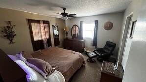 Ein Schlafzimmer mit Bett, Schminktisch, Stuhl und Deckenventilator.