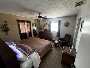 Ein Schlafzimmer mit Bett, Schminktisch, Stuhl und Deckenventilator.