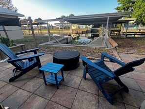 A patio with Adirondack chairs, a small table, and a round table. - Quiet and Cozy Waterfront rental; with dock to Lock access into Lake Okeechobee (Okeechobee)
