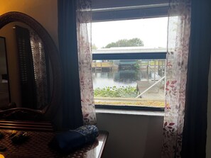 A room with a large mirror, a window with floral curtains, and a view of a bridge and greenery outside. - Quiet and Cozy Waterfront rental; with dock to Lock access into Lake Okeechobee (Okeechobee)