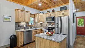 Eine Küche mit Holzschränken, Granit-Arbeitsplatten, Edelstahlgeräten und einer Holzbalkendecke.