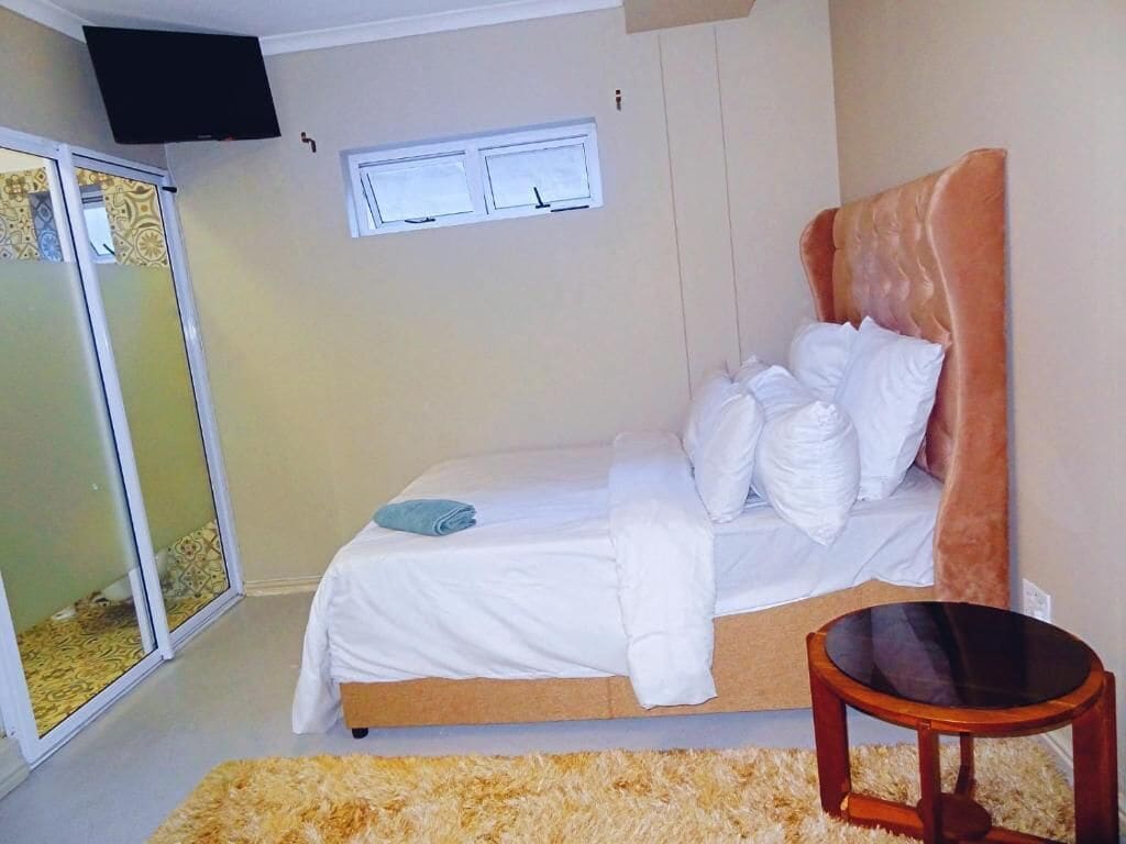 Une chambre à coucher avec un lit, une petite table, un téléviseur et une porte coulissante.