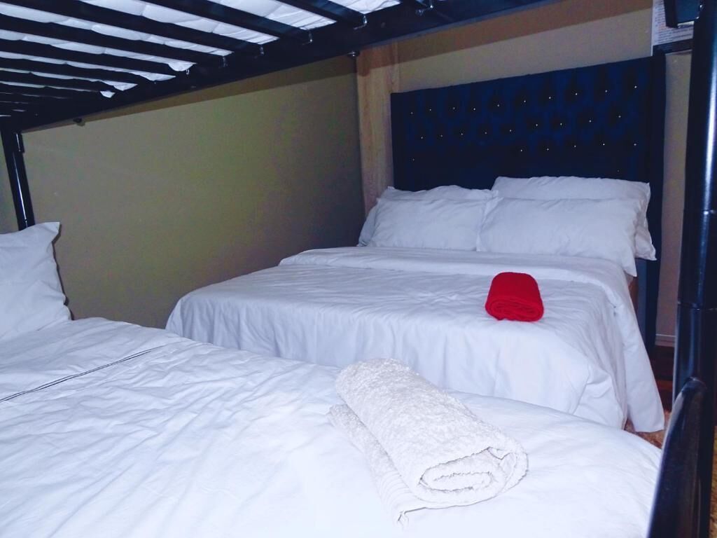 A room with two beds, each with white bedding and a red pillow.