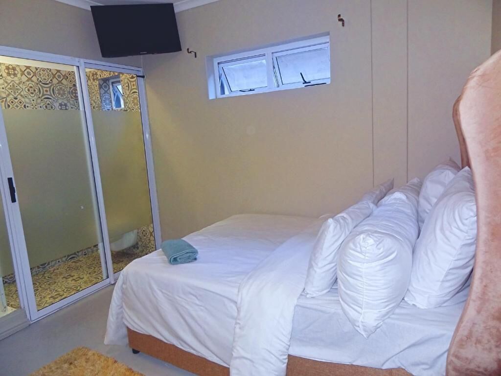 A bedroom with a bed, a window, a TV, and a sliding door.