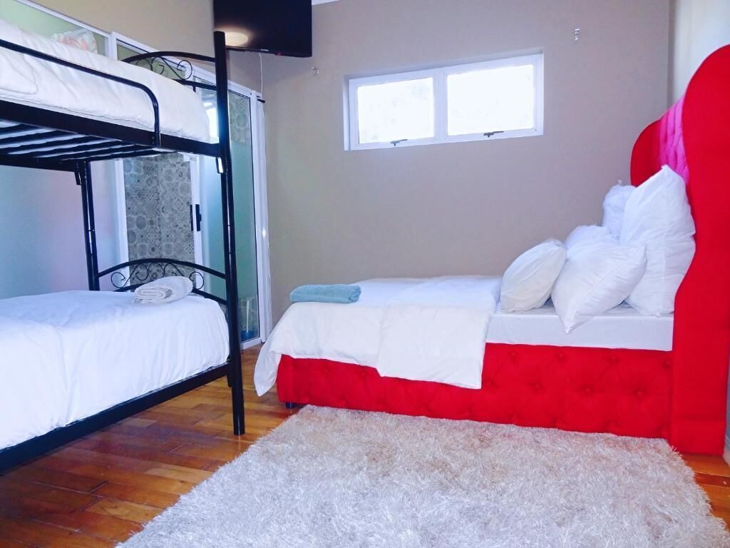 Une chambre avec des lits superposés, une fenêtre et un tapis blanc.