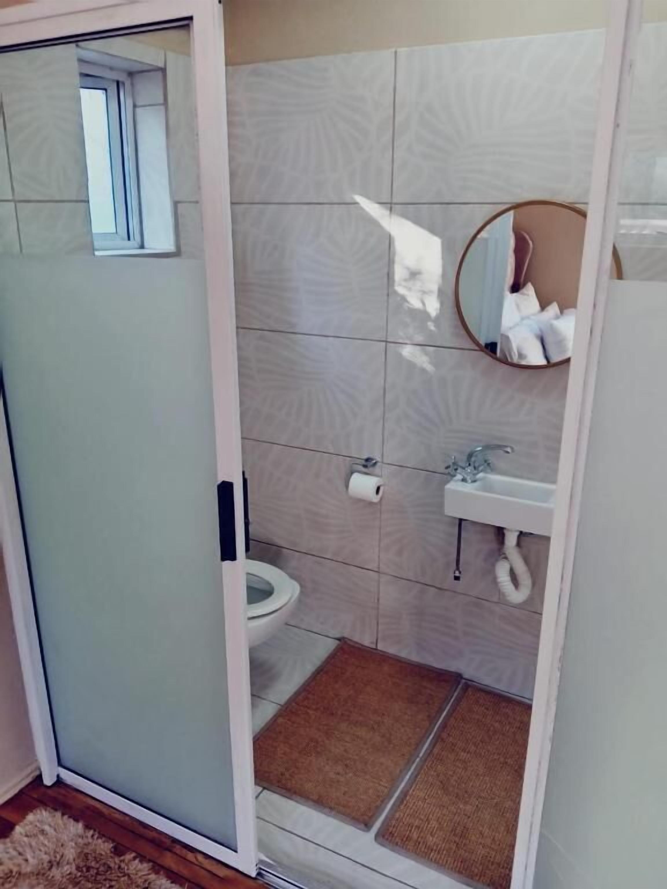 A bathroom with a toilet, sink, and mirror.