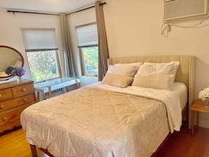 Un dormitorio con cama, cómoda, escritorio y ventanas.