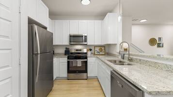 A modern kitchen with white cabinets, stainless steel appliances, a granite countertop, and a built-in oven.